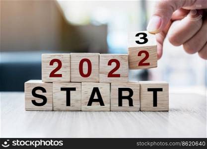 hand flipping block 2022 to 2023 START text on table. Resolution, strategy, goal, motivation, reboot, business and New Year holiday concepts