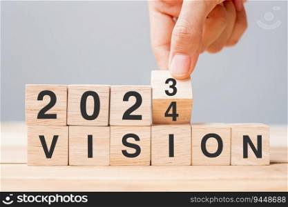hand flipping block 2023 to 2024 VISION text on table. Resolution, strategy, goal, motivation, reboot, business and New Year holiday concepts