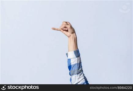Hand gesturing the letter J in sign language on an isolated background. Man’s hand gesturing the letter J of the alphabet isolated. Letters of the alphabet in sign language