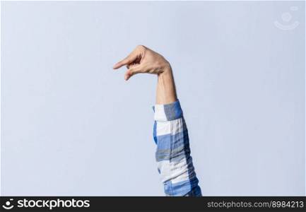 Hand gesturing the letter Q in sign language on an isolated background. Man&rsquo;s hand gesturing the letter Q of the alphabet isolated. Letter Q of the alphabet in sign language