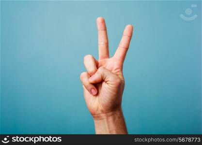Hand gesturing victory on a blue background