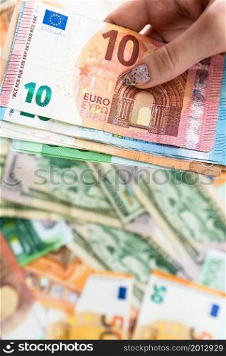 Hand giving money like bribe or tips isolated on banknotes background. EURO and USD currency banknotes close up. Reward for hard work, inflation, finance and business concept