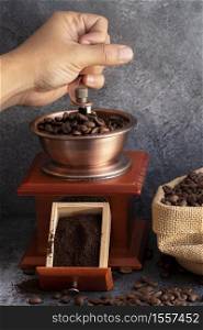 Hand grinding coffee beans in wooden grinder