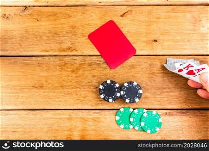 Hand having Ace and King on wooden background, poker chips, dealer, gambler, poker concept