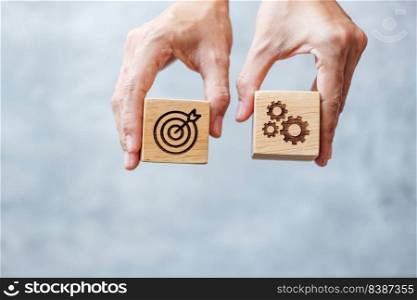 hand hold dartboard and gear block with business goal, strategy, target, mission, action, objective, aim and success concept