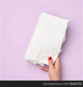 hand hold folded wrapping crumpled white paper on purple background