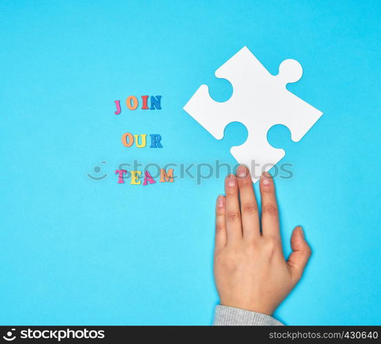 hand hold large white puzzles and the inscription join our team on a blue background, concept of recruitment