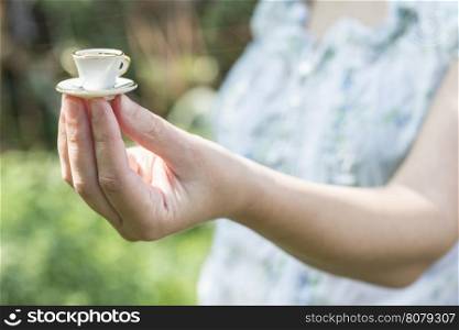 Hand hold very small cup of coffee. Miniature cup