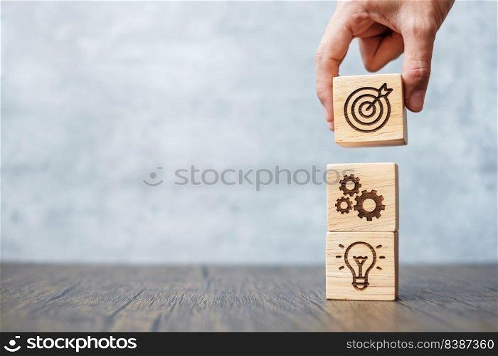 hand hold wood block with business goal, strategy, target, mission, action, objective, teamwork and idea concept