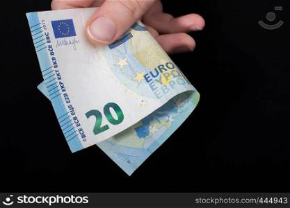 Hand holding 100 euro money cash isolated on black background