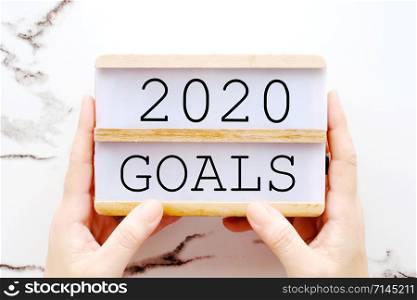 Hand holding 2020 goals on wooden box over marble background, banner, business new year, aim to success in business