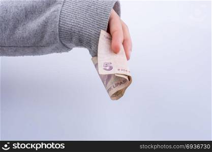 Hand holding 5 Turksh Lira banknote on white background