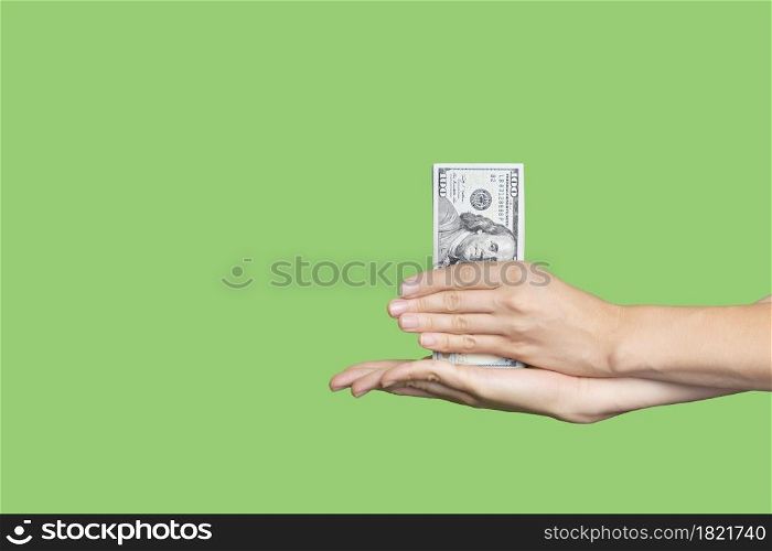 Hand holding a big stack of banknotes isolated on green background. Wealth or loan concept. Banner with copy space.. Hand holding a big stack of banknotes isolated on green background. Wealth or loan concept. Banner with copy space