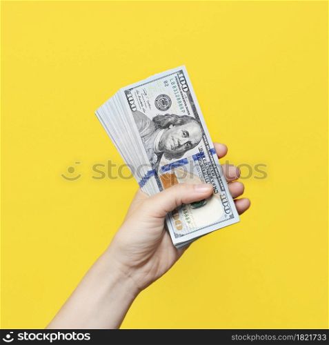 Hand holding a big stack of banknotes isolated on yellow background. Wealth or loan concept.. Hand holding a big stack of banknotes isolated on yellow background. Wealth or loan concept