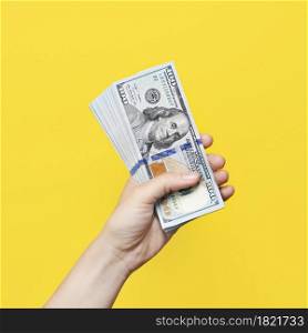 Hand holding a big stack of banknotes isolated on yellow background. Wealth or loan concept.. Hand holding a big stack of banknotes isolated on yellow background. Wealth or loan concept