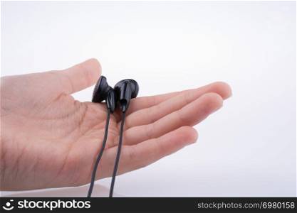 Hand holding a black earphone on a white background