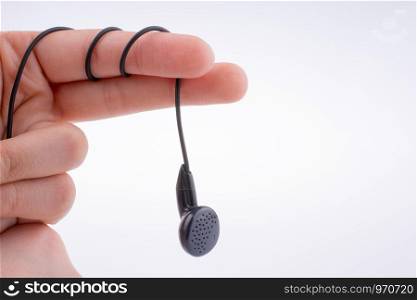 Hand holding a black earphone on a white background