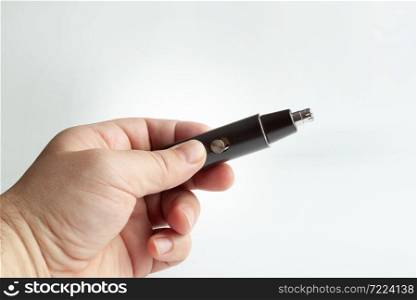 Hand holding a black nose trimmer. Close up. Isolated on a grey background.