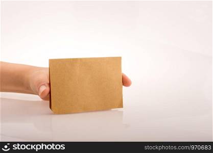 Hand holding a brown sheet of paper on a white background