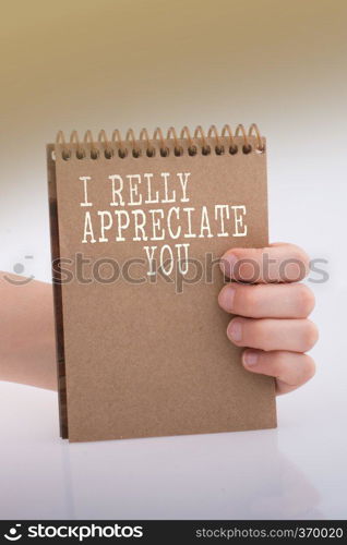 Hand holding a brown spiral notebook on a white background