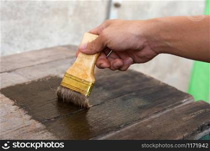 hand holding a brush Painting wooden timber boards surface with Wood Stain