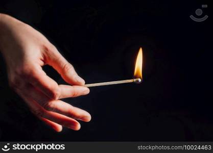 Hand holding a burning match, isolated on black background. Burning Match, Black Background
