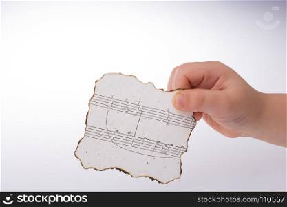 Hand holding a burnt paper with musical