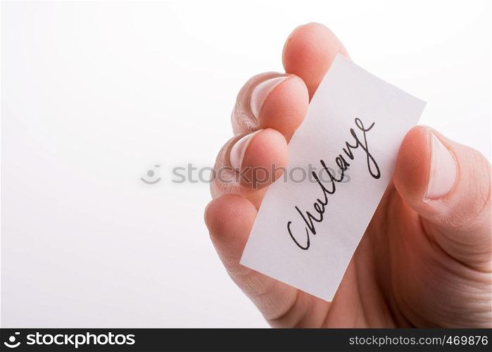 Hand holding a challenge written paper on a white background