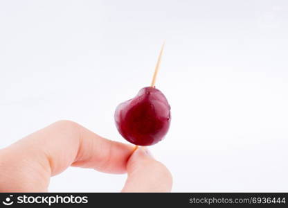 Hand holding a Cherry on a white background