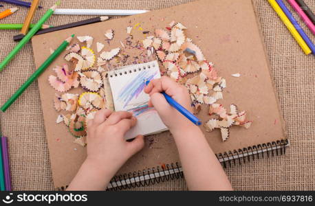 Hand holding a color pencil on spiral notebooks with pencil trash