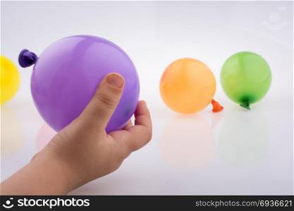 Hand holding a Colorful small balloon with colorful baloons on the white background