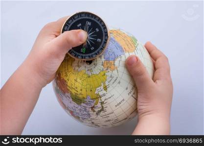 Hand holding a compass and a globe on white background