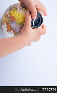 Hand holding a compass and a globe on white background