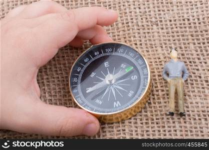 Hand holding a compass beside a figurine