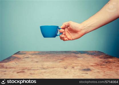 Hand holding a cup at table