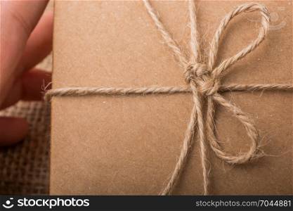 Hand holding a gift box of brown color on linen canvas