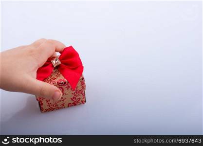 Hand holding a gift box with a red ribbon
