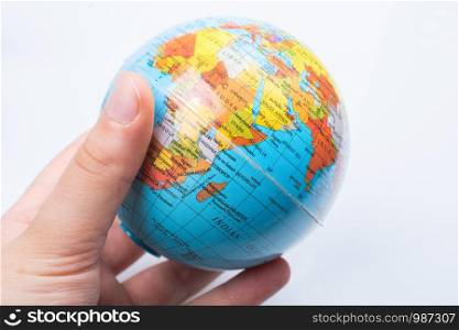 Hand holding a globe model on a white background