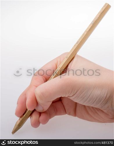 Hand holding a gold color pencil on a white background
