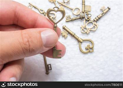 Hand holding a heart shaped key on white background over other keys