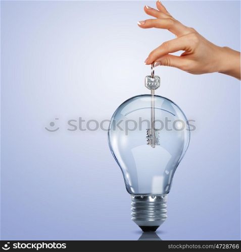 Hand holding a key and putting it inside a light bulb