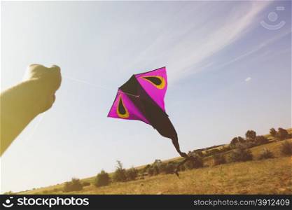 Hand holding a kite against the sky, tinted photo