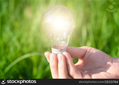 Hand holding a lamp on a background of green grass. Concept of green electricity, startup, creative eco idea. A place to meditate or reboot.. Hand holding a lamp on a background of green grass. Concept of green electricity, startup, creative eco idea. A place to meditate or reboot