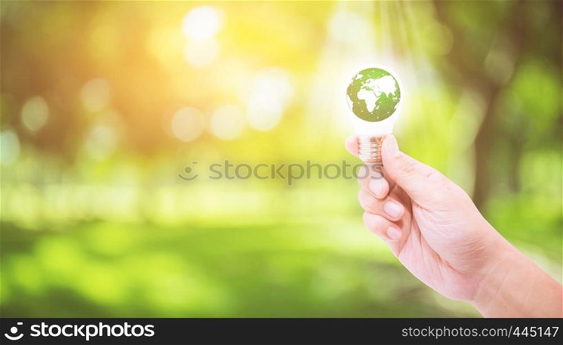 Hand holding a light bulb with energy green world inside on nature background, environment and ecology concept - Elements of this image furnished by NASA.