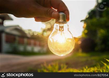hand holding a light bulb with sunset power concept