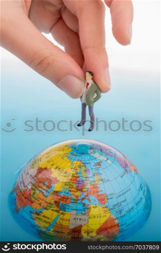 Hand holding a little figurine on the top of the globe in water