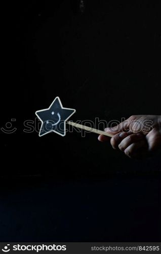 Hand holding a magic wand with smile face