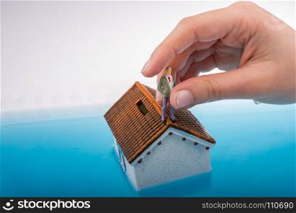 Hand holding a man figurines in water by on the roof of a model house