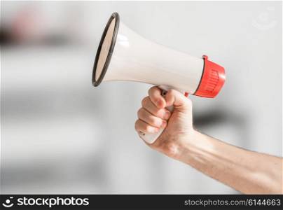 Hand holding a megaphone in an office building
