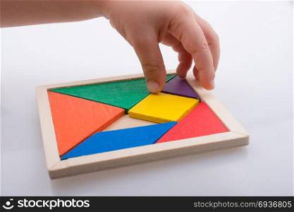hand holding a missing piece in a tangram puzzle